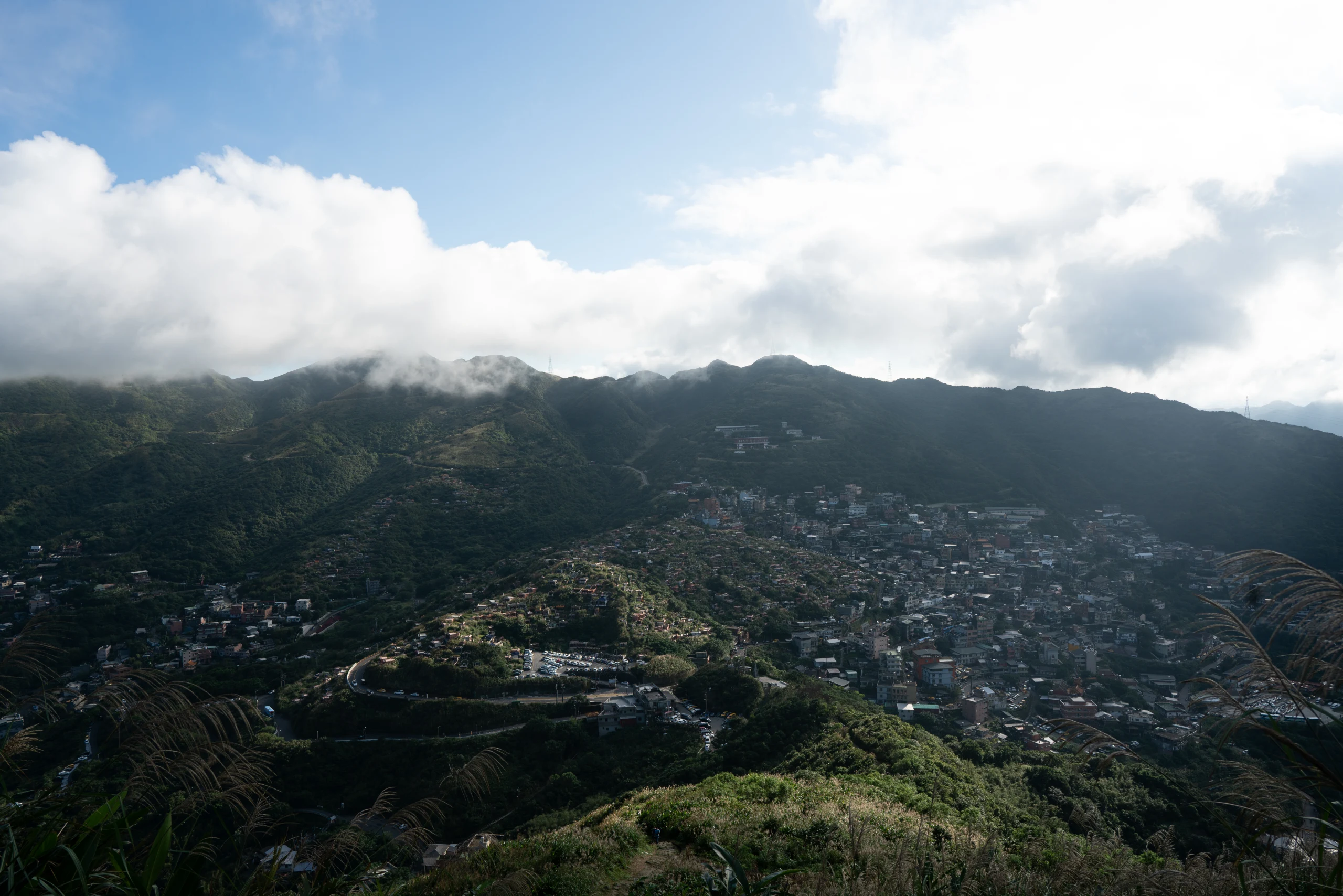 Clouds move across green mountain settlements, temples, and sea views above Jiufen.