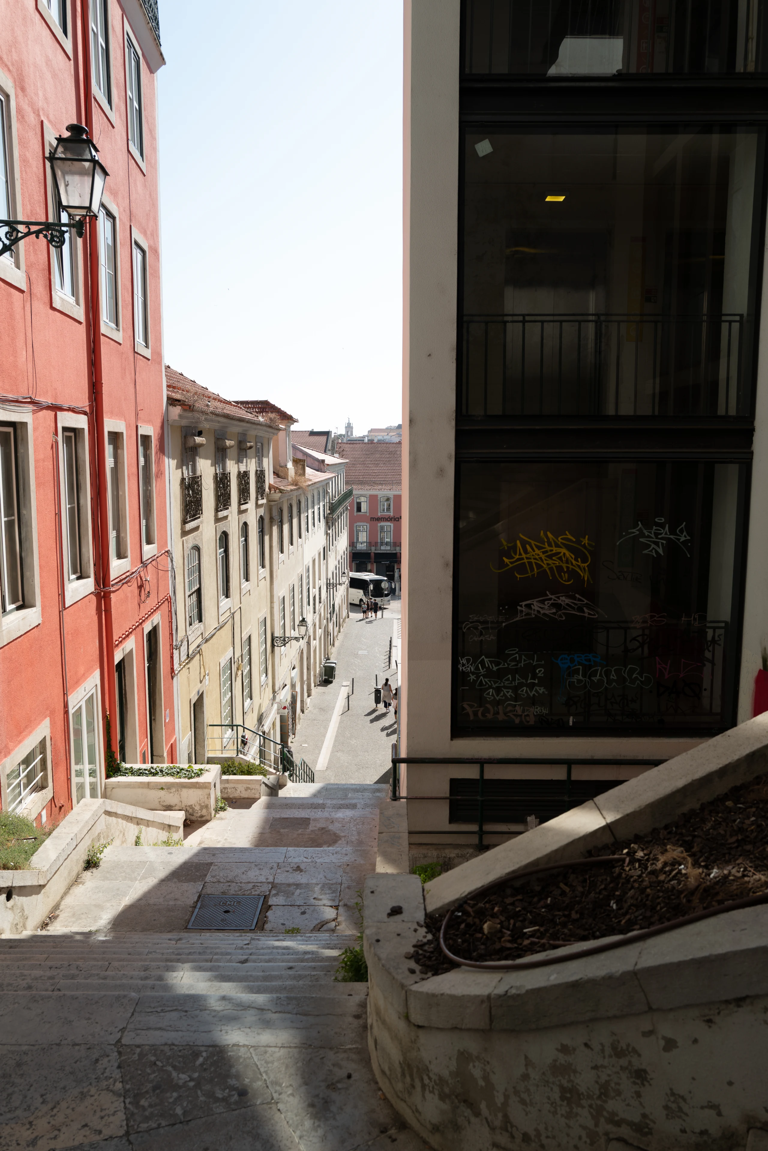 A steep stairway descends beside a red building.