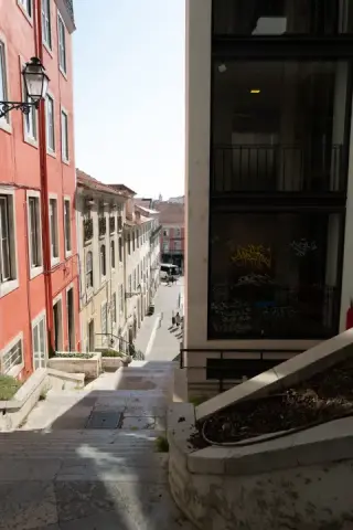 A steep stairway descends beside a red building.