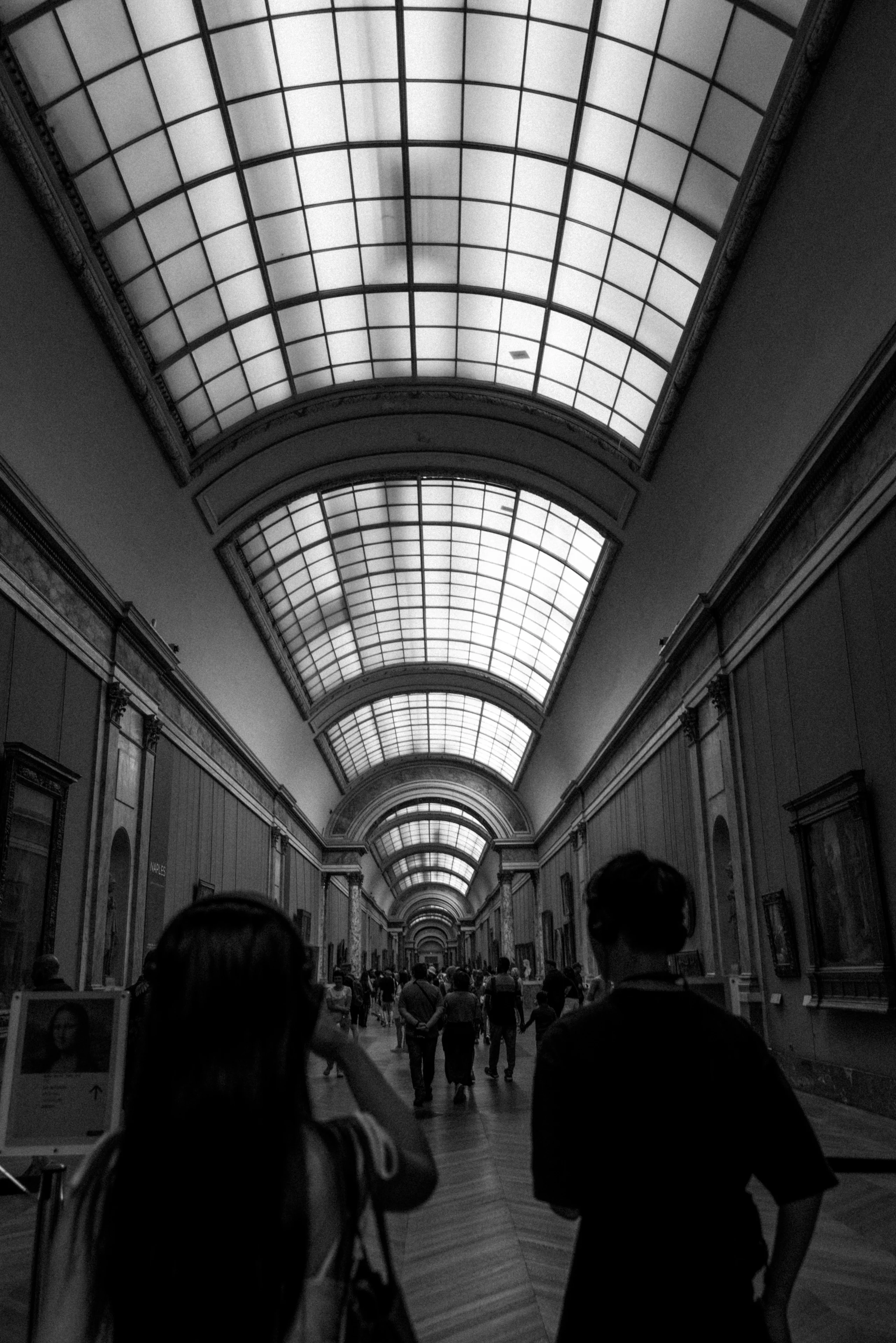 Silhouetted figures beneath a vaulted arcade in black and white.