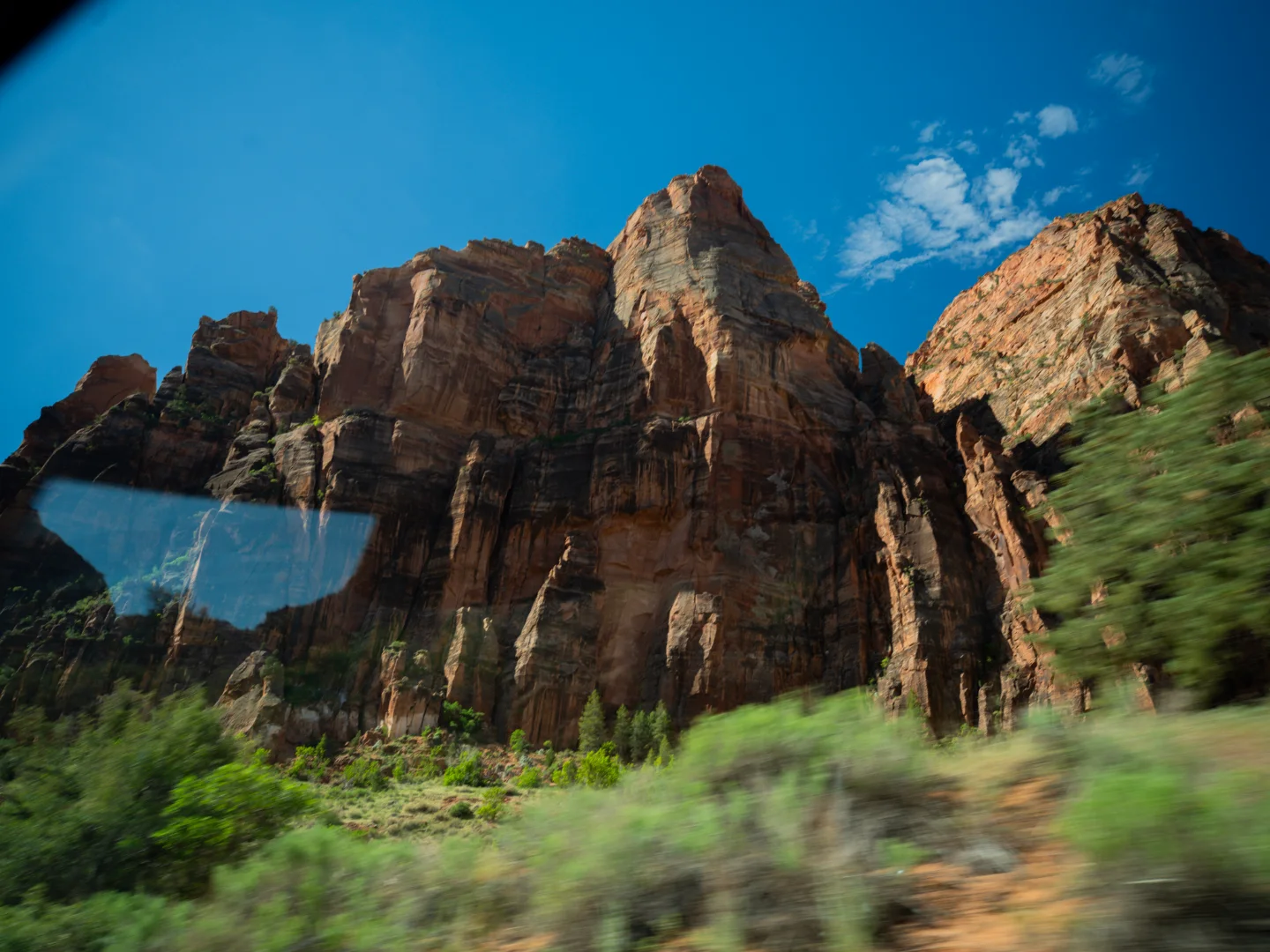 Zion cliffs blur past a vehicle window.