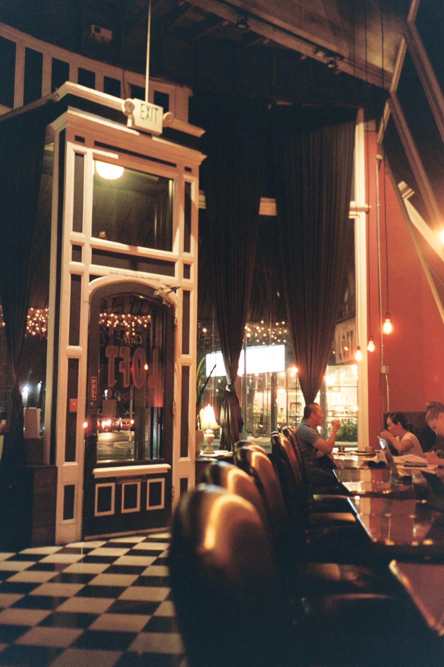 Ornate restaurant entrance with a checkered floor at night.