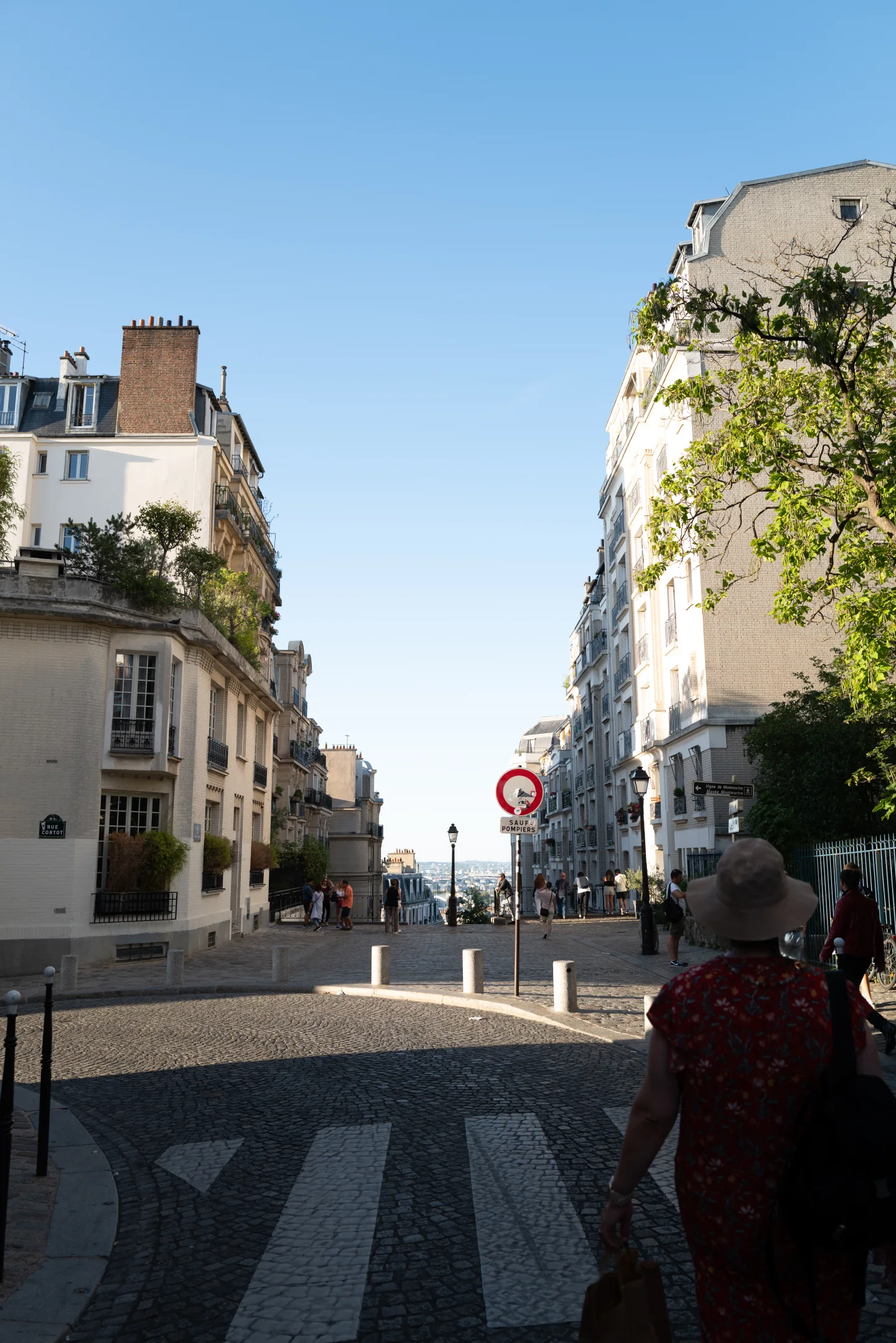 Woman walking along a sunlit Paris street.