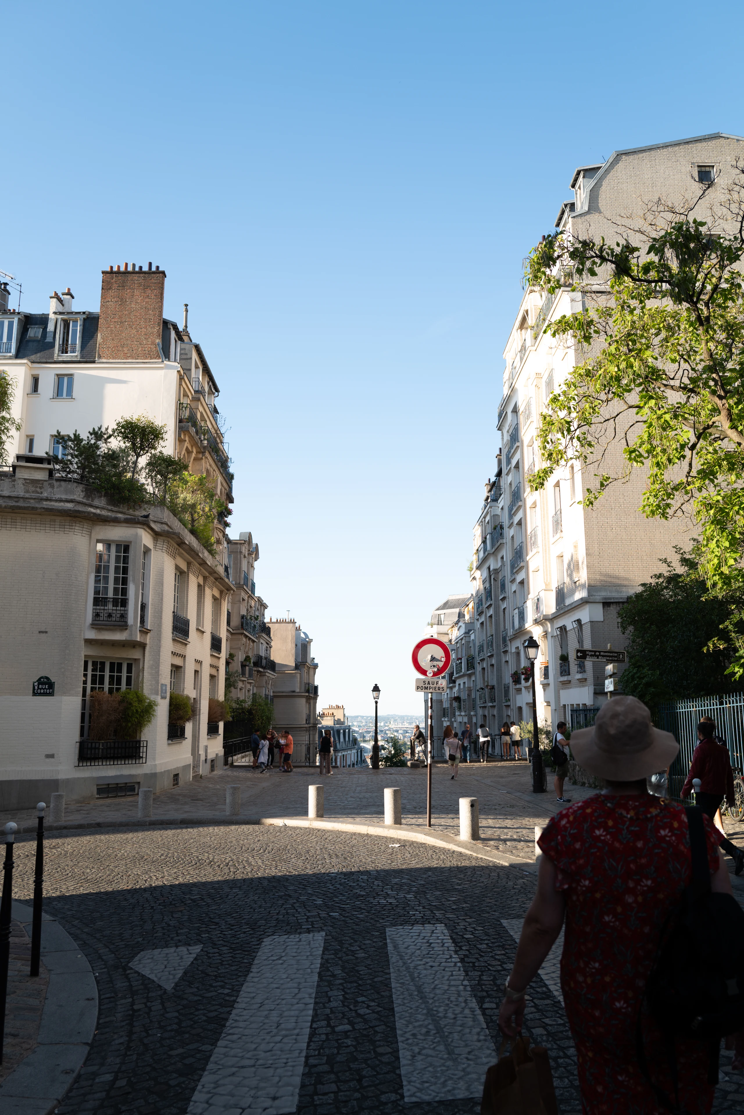 Woman walking along a sunlit Paris street.