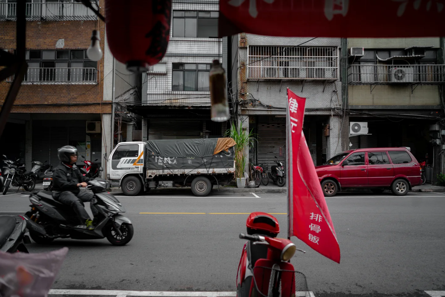 Scooters and red flags lining a Taipei street.