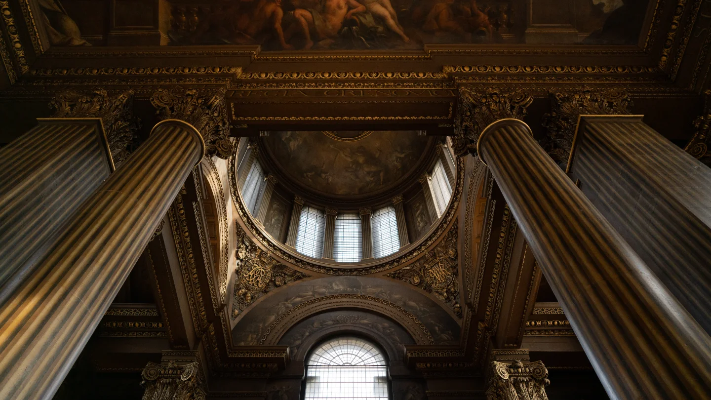 Stone columns rise toward an ornate painted dome and high arched windows.