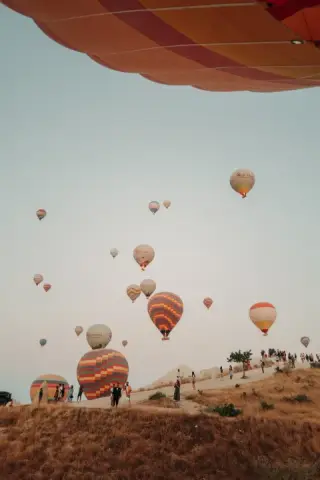 Hot-air balloons beneath a pale sky and the edge of a balloon overhead.