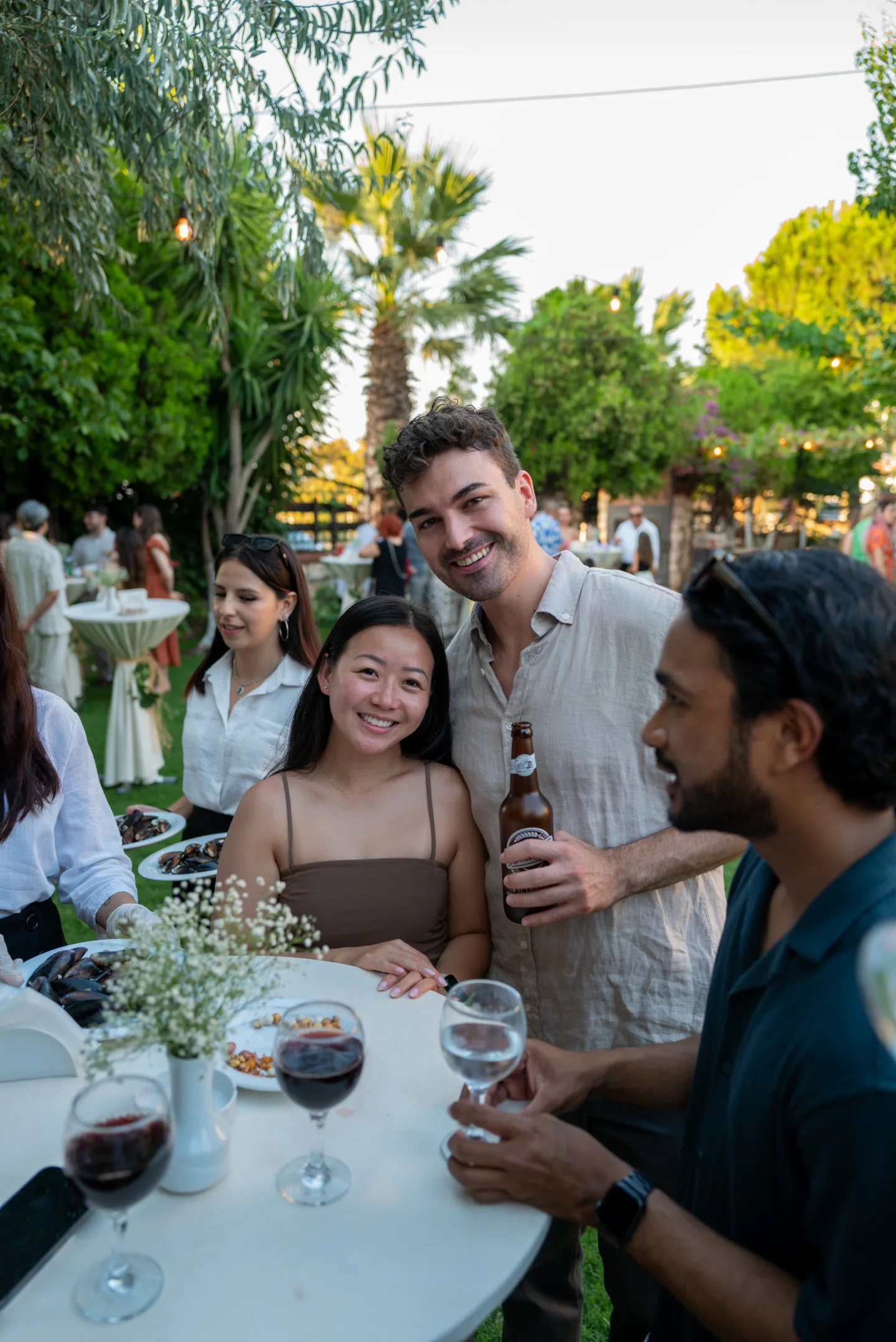 Friends gather around a high table at a garden reception.