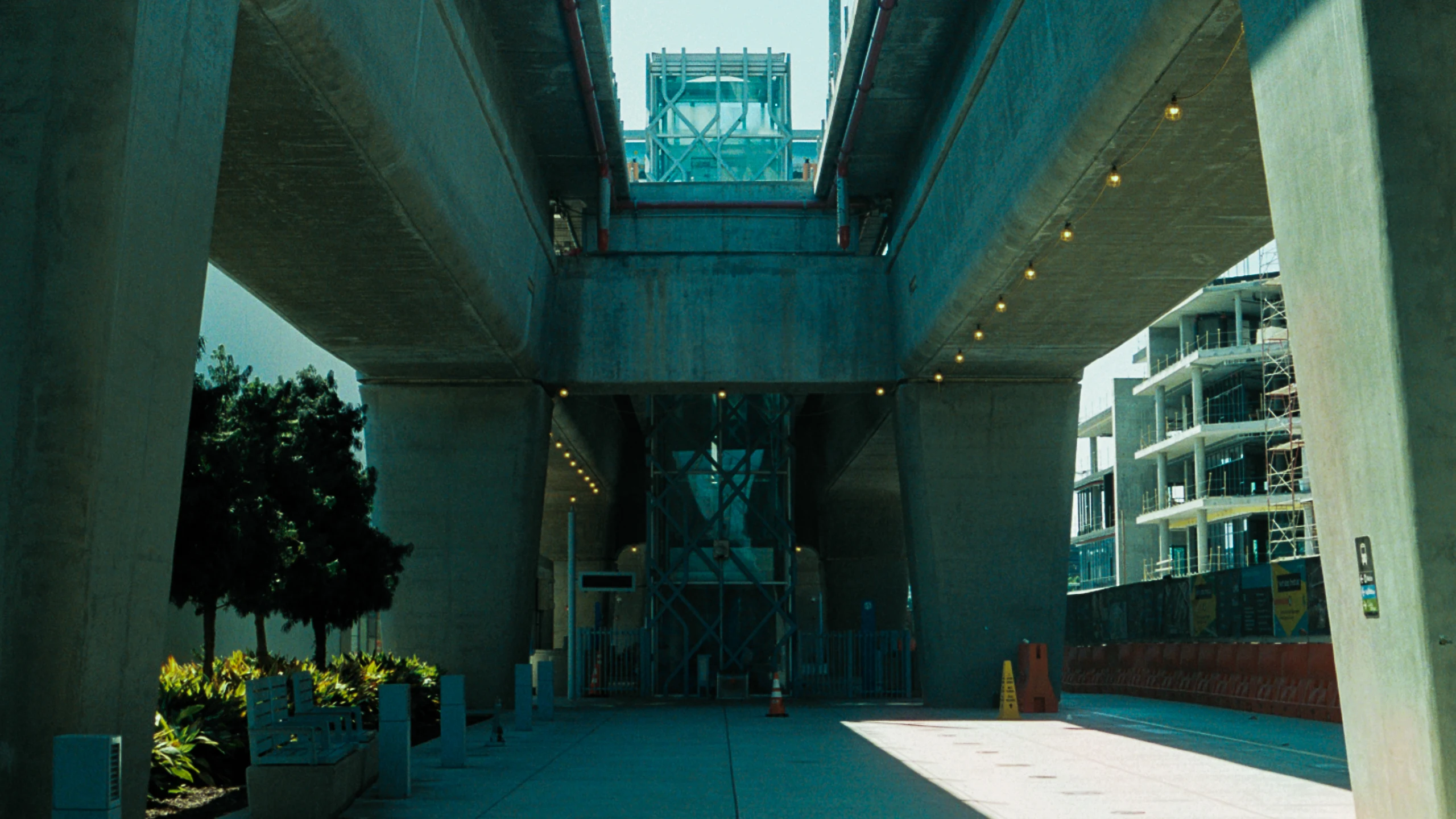 A modern concrete passage opens toward trees and blue sky.