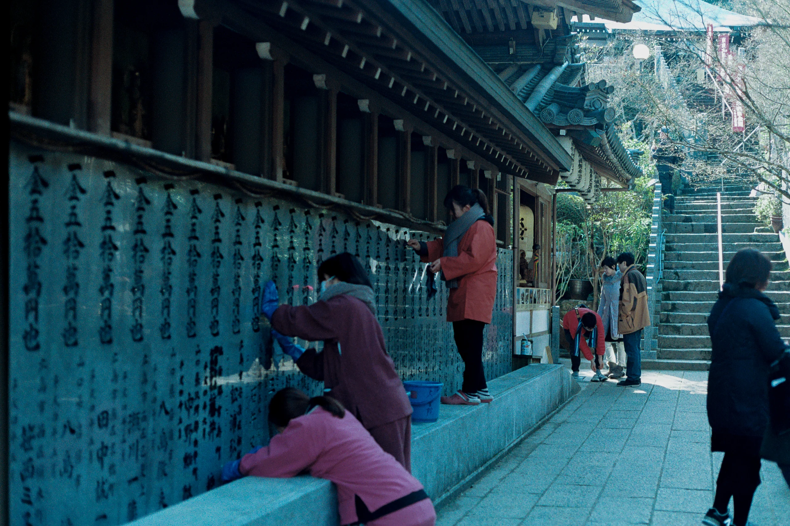 Visitors pause beside rows of inscriptions at a shrine.