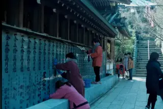 Visitors pause beside rows of inscriptions at a shrine.