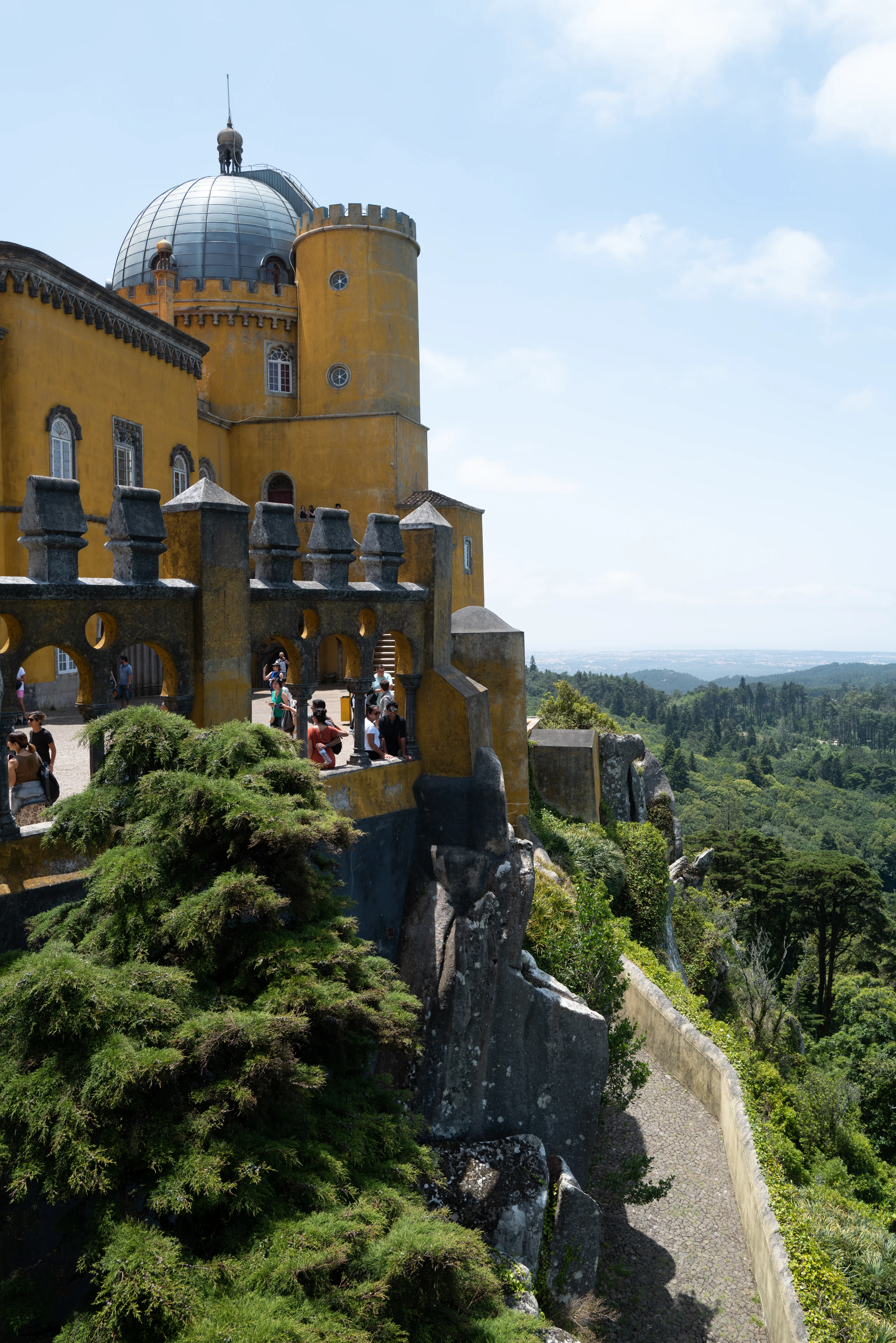 A yellow palace tower rises above dense green trees.