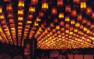 Hundreds of warm lanterns fill a temple interior.