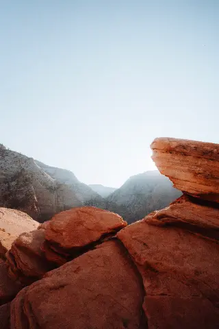 A large red boulder sits in the foreground above a sweeping Zion canyon view.