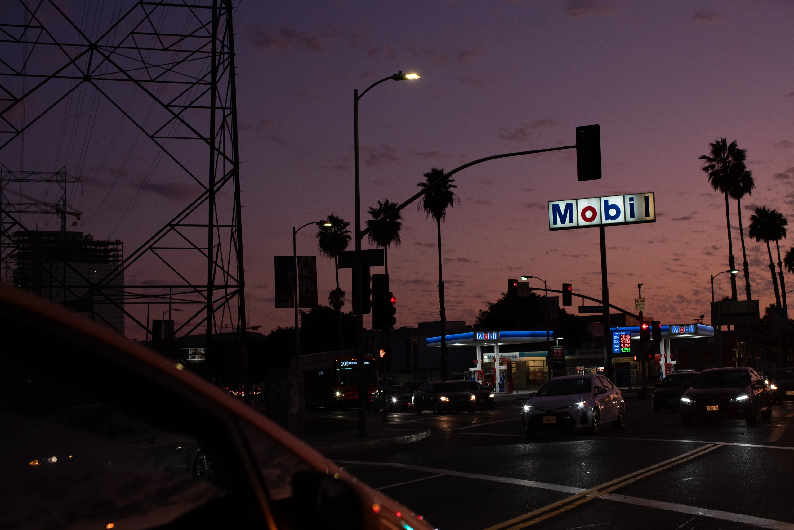 A neon gas-station sign and palms meet the violet Los Angeles dusk.