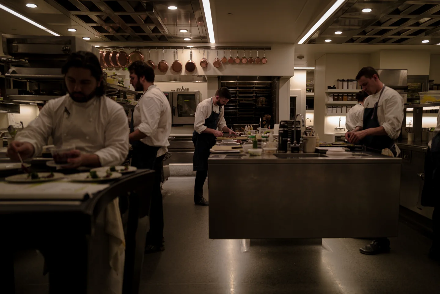 Cooks work across the open kitchen of a restaurant.