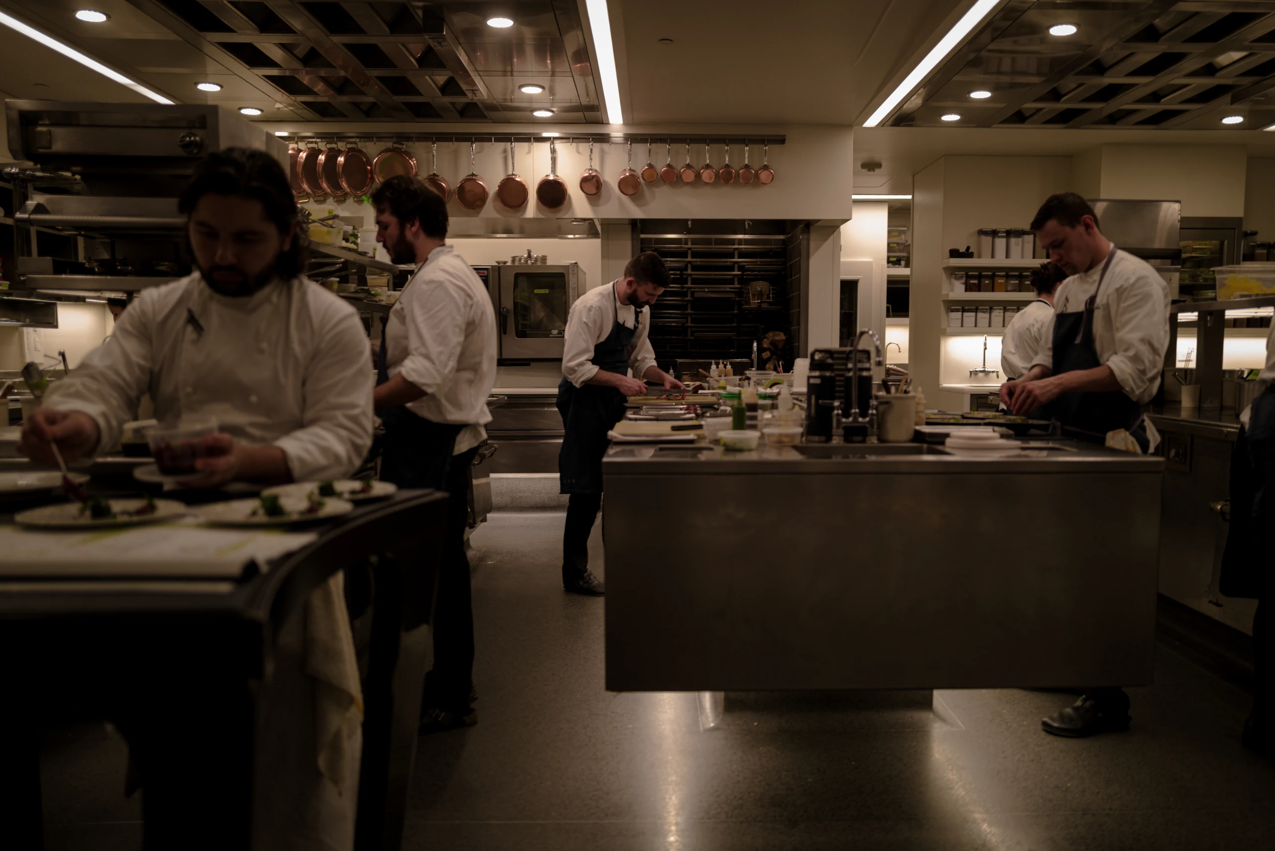 Cooks work across the open kitchen of a restaurant.