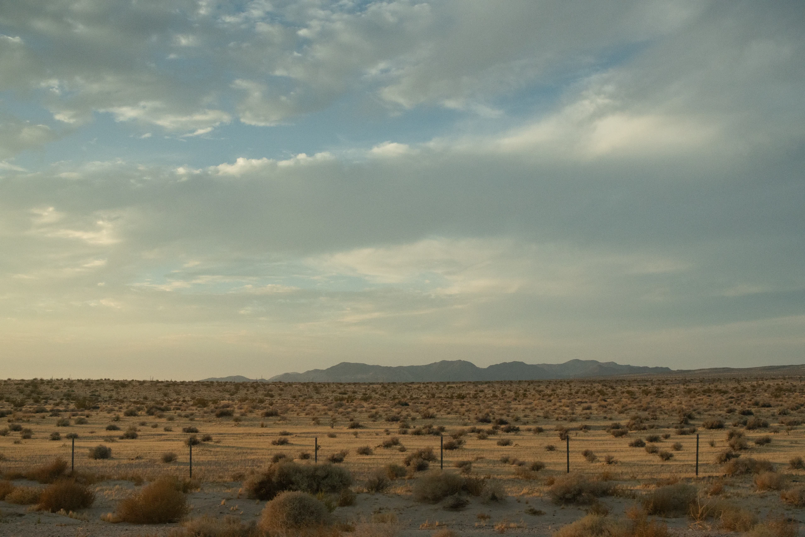 A broad desert plain stretches beneath gathering storm clouds near Zion.