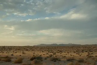 A broad desert plain stretches beneath gathering storm clouds near Zion.