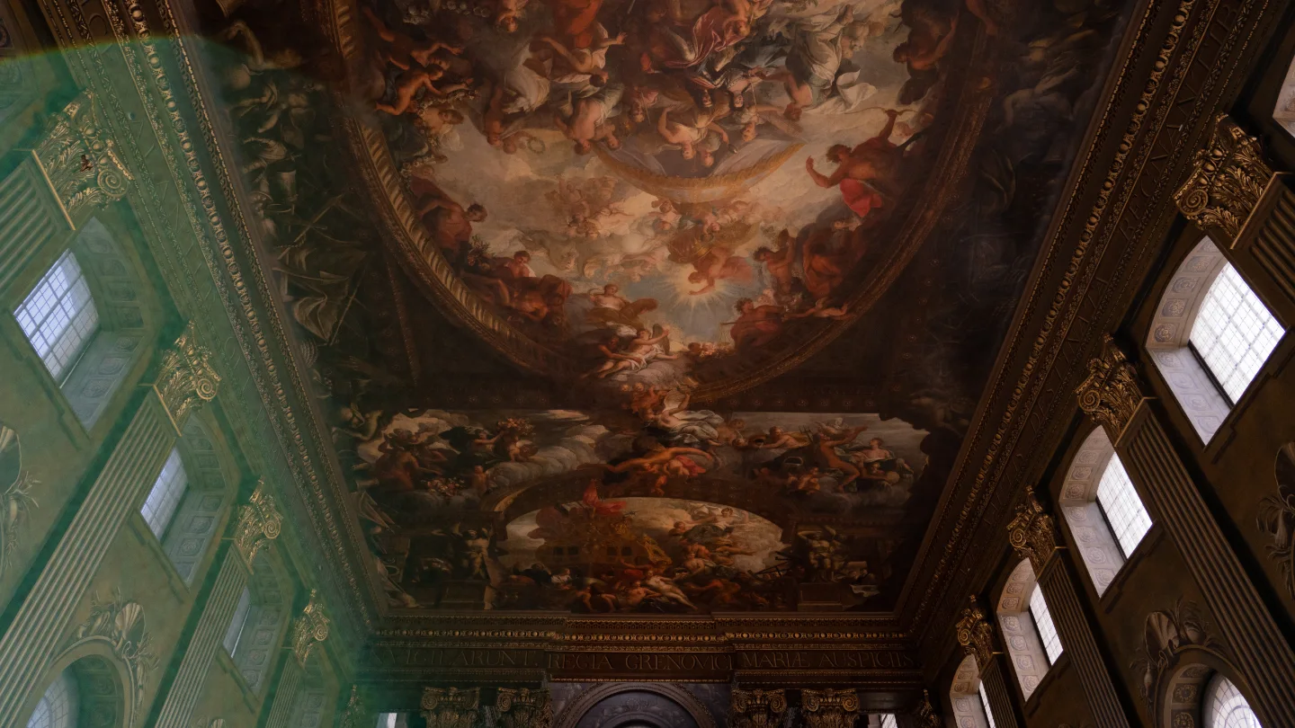 A richly painted ceiling stretches above tall green walls and clerestory windows.