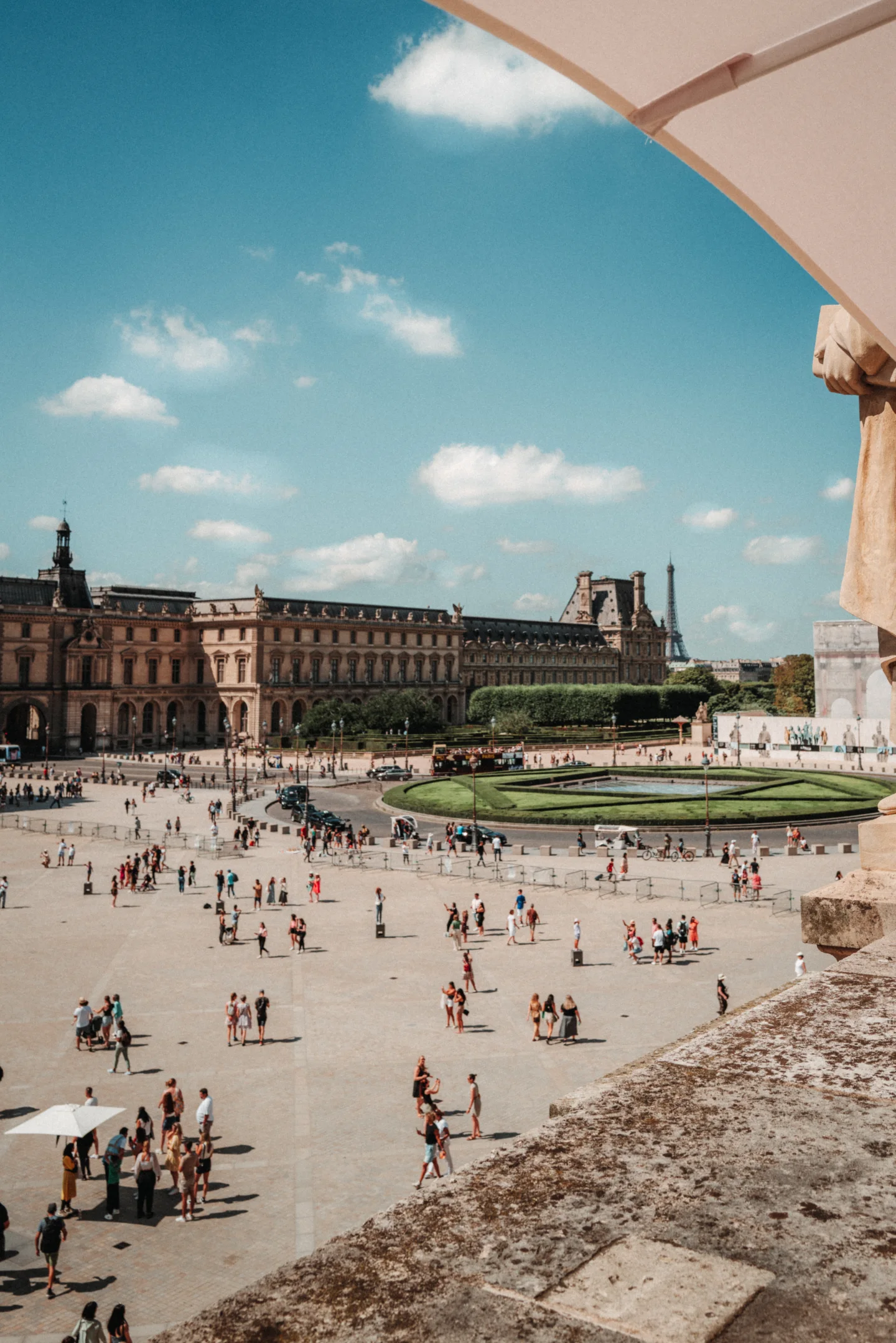 Crowds crossing the Louvre courtyard beside the reflecting pools.