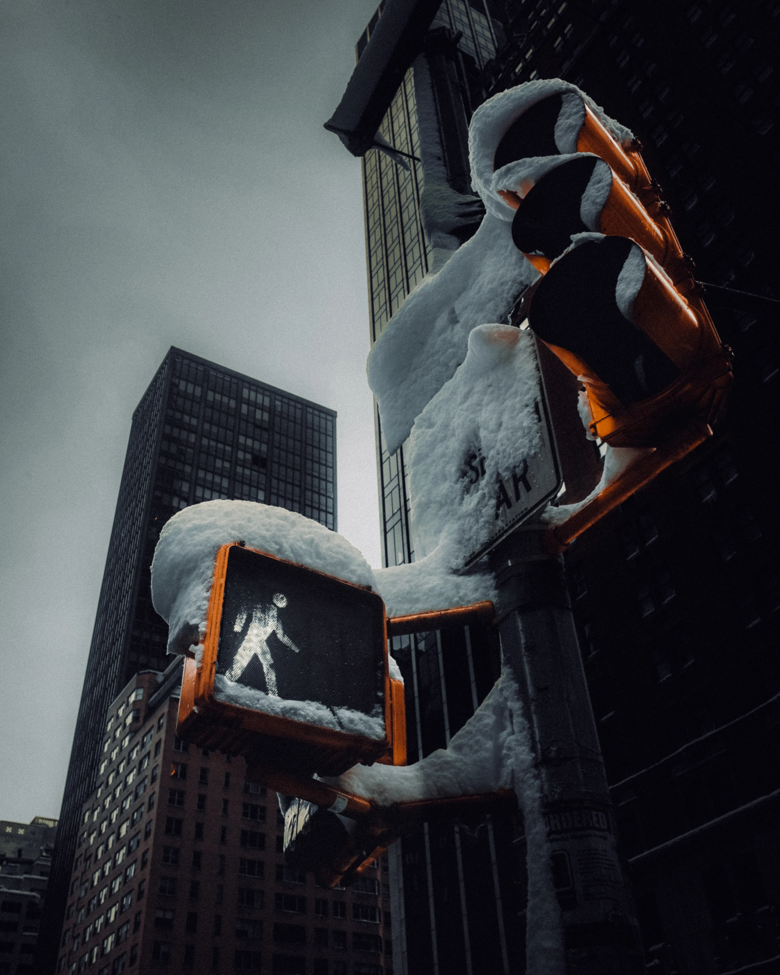 Pedestrian signal and traffic lights heavily capped with snow