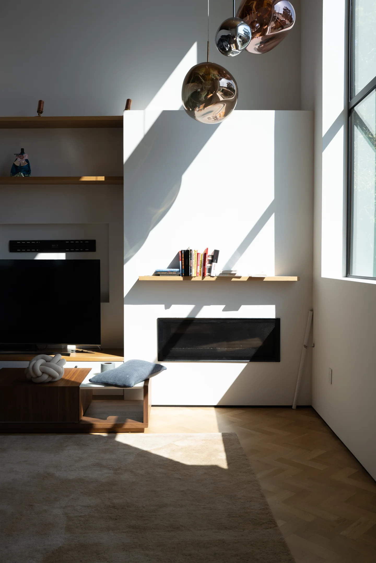 Sunlight crosses a minimalist living room and fireplace.