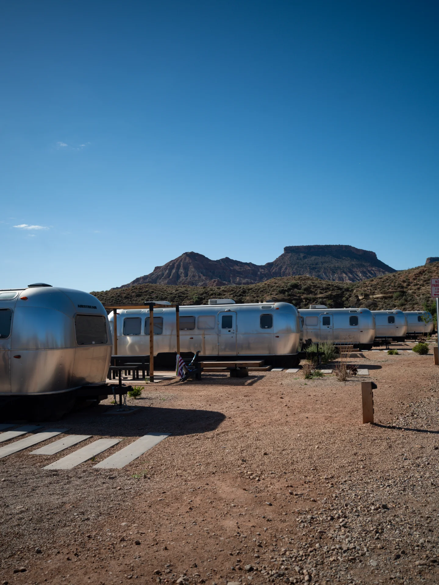 A silver trailer sits on red earth beneath a dark desert sky.