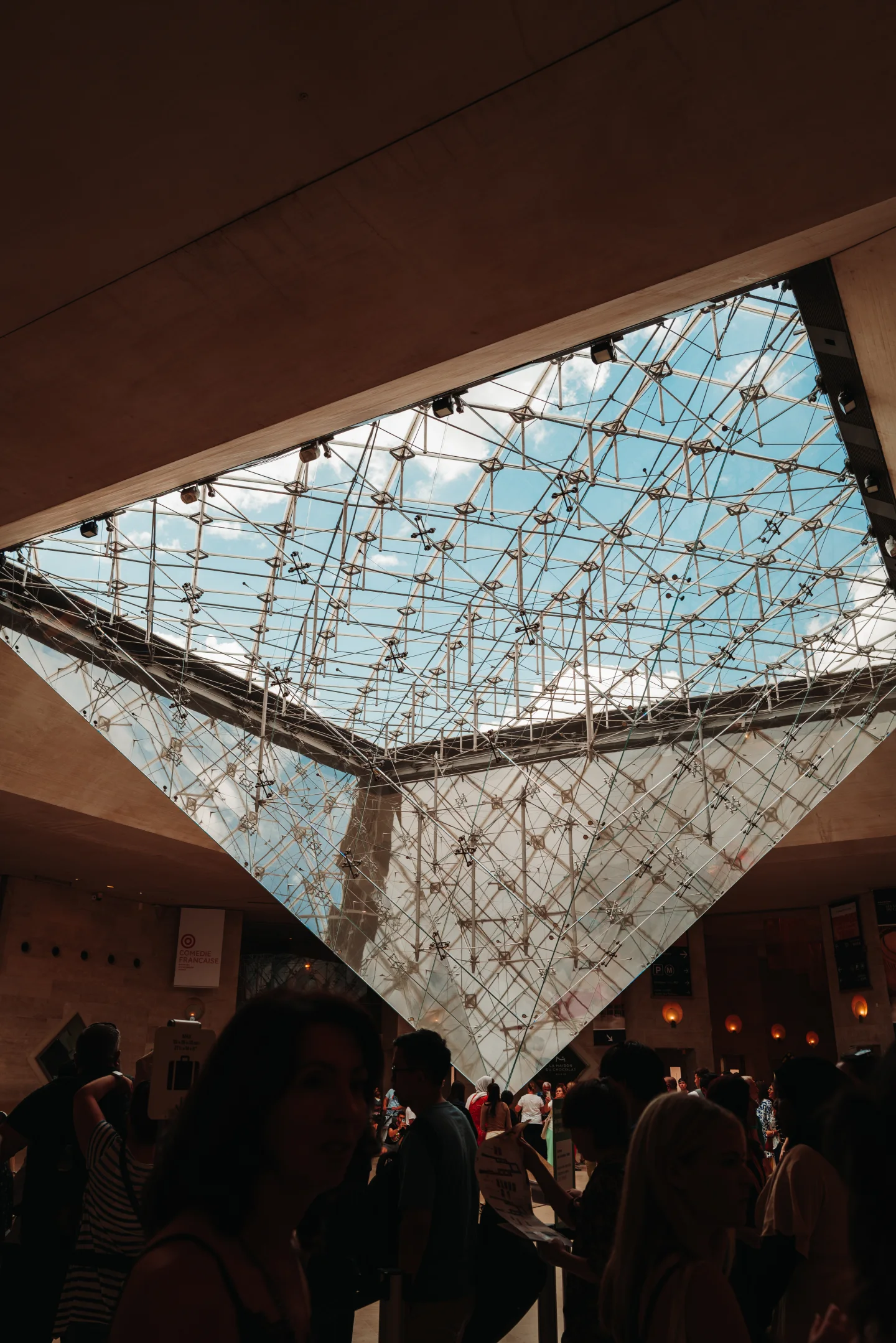 Inverted Louvre pyramid suspended above a dark crowd.