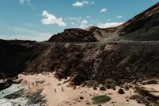 Crowded beach tucked beneath high cliffs.