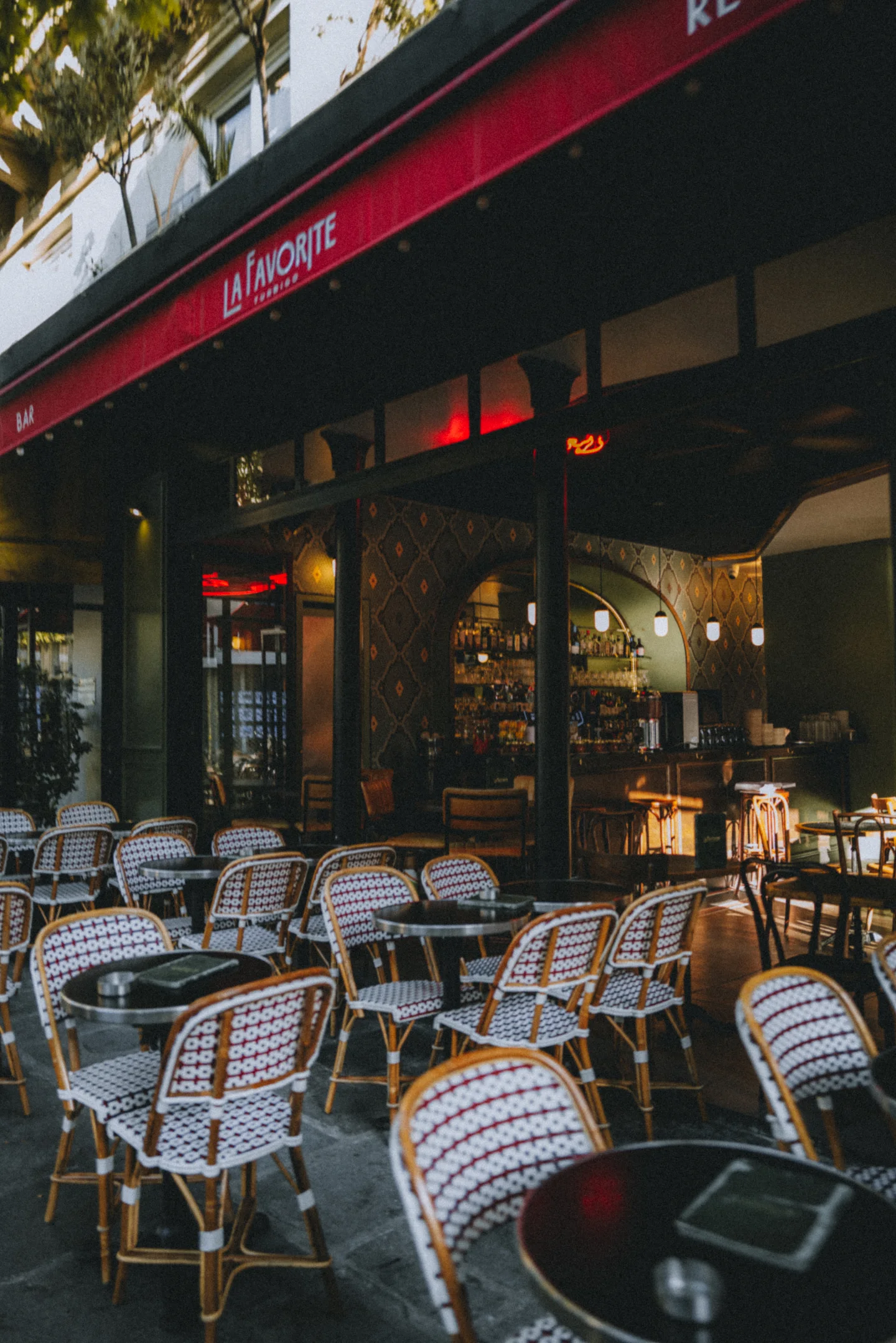 Empty café chairs arranged beneath a red awning.