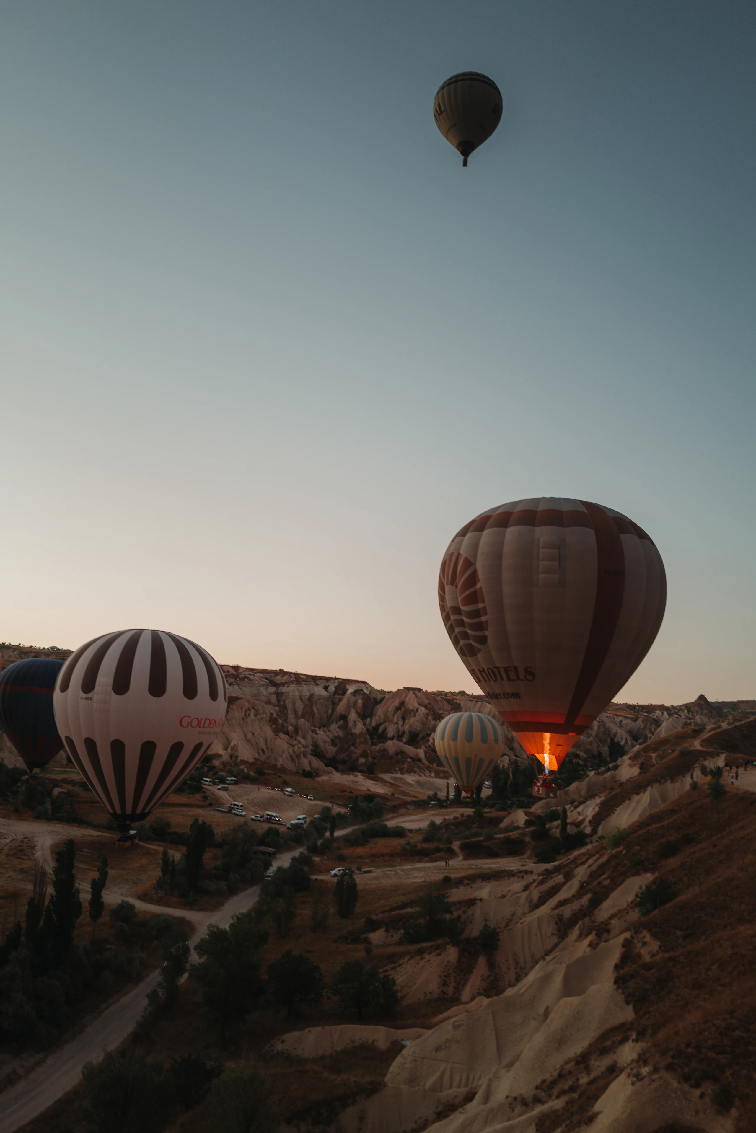 Hot-air balloons floating above a Cappadocia valley.