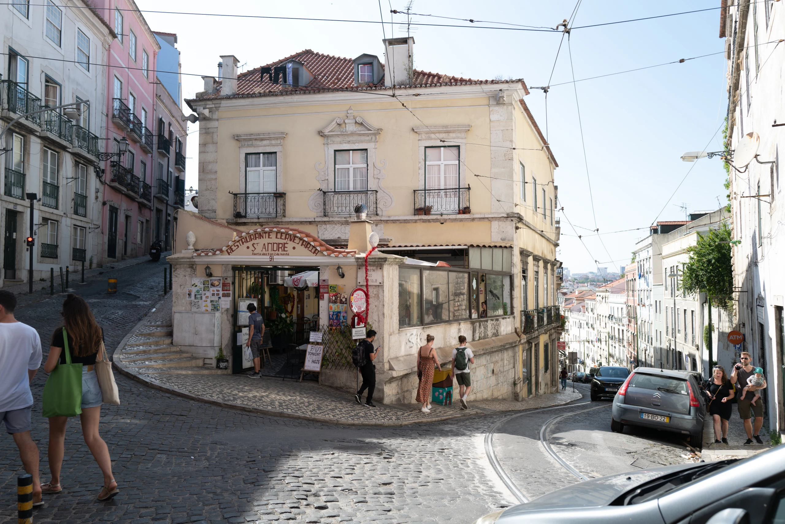 A corner cafe sits above a curving downhill street.