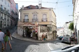 A corner cafe sits above a curving downhill street.