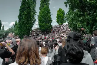 A large crowd fills the amphitheater steps between tall trees at Mauerpark in Berlin.