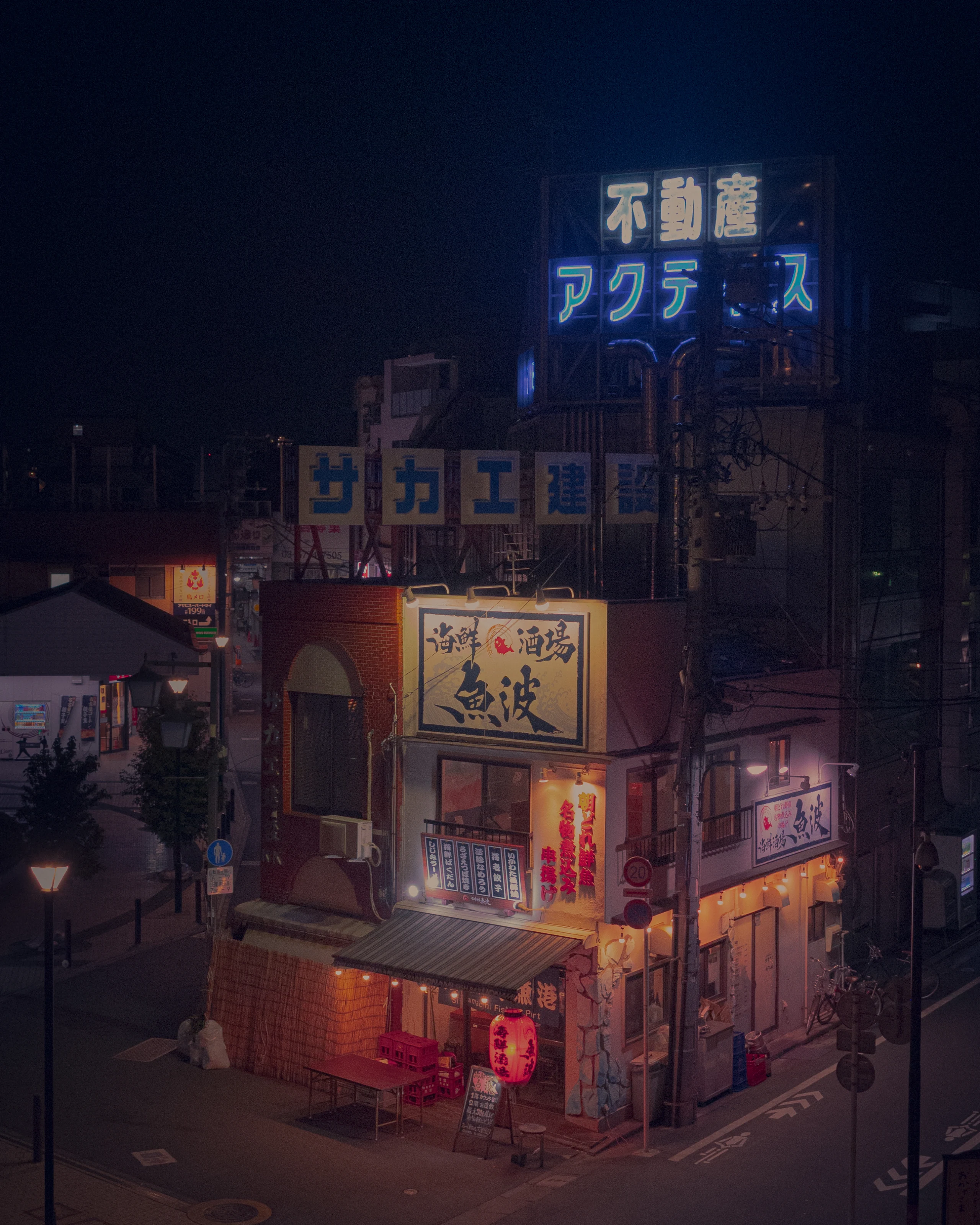 A corner restaurant glows violet and red beneath rooftop signs.