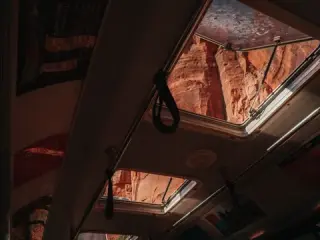 Red Zion cliffs are visible through the windows and glass roof of a vehicle.