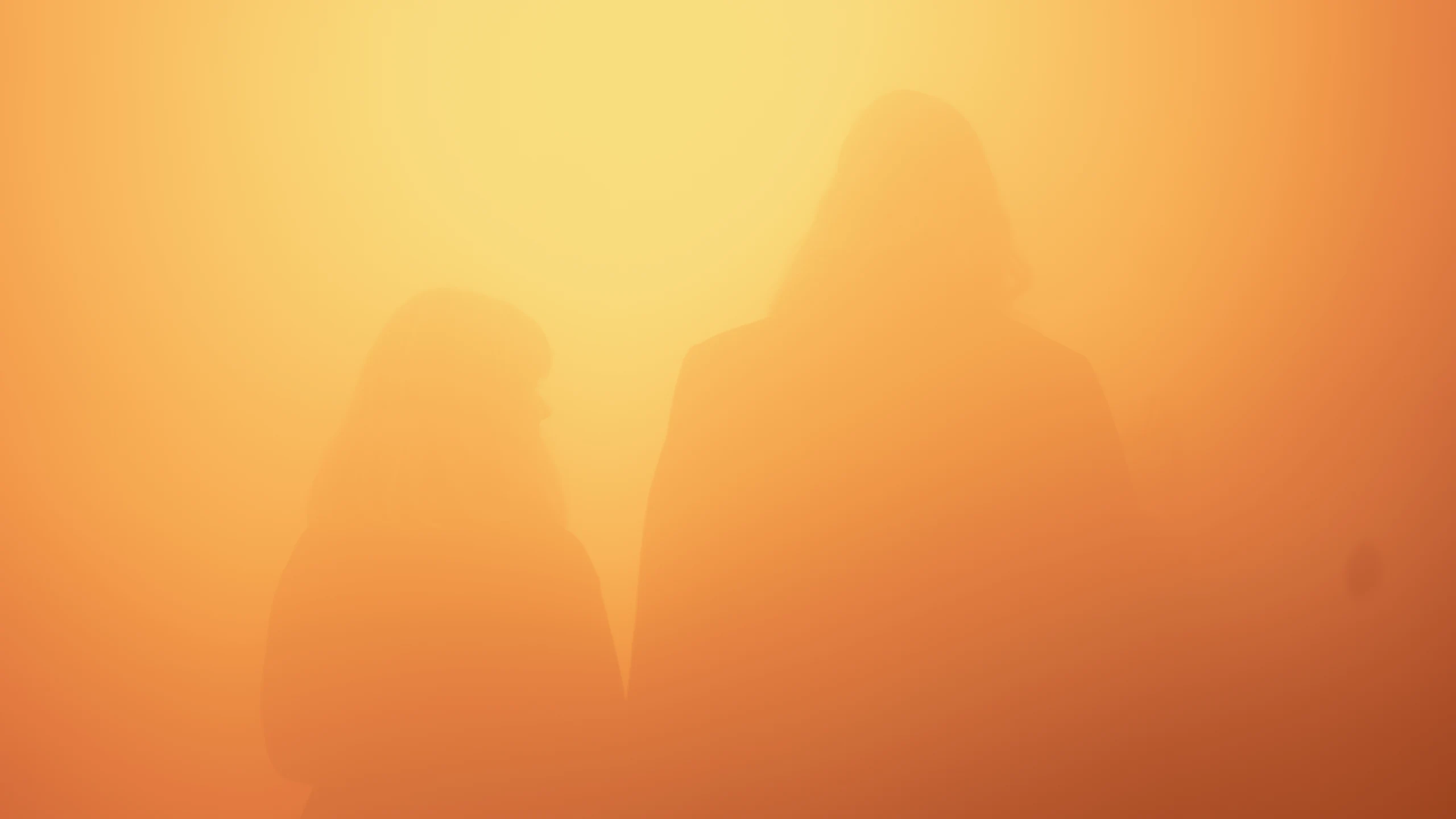 Two faint human silhouettes behind a glowing orange translucent surface.