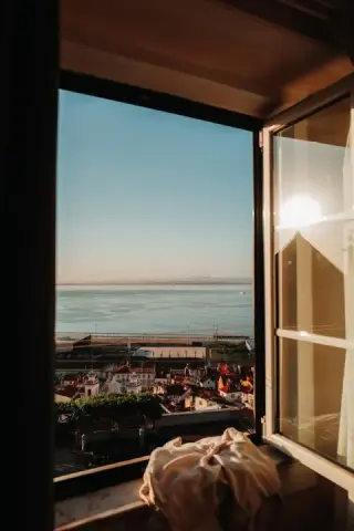 Morning light enters an open window above Lisbon and the river.