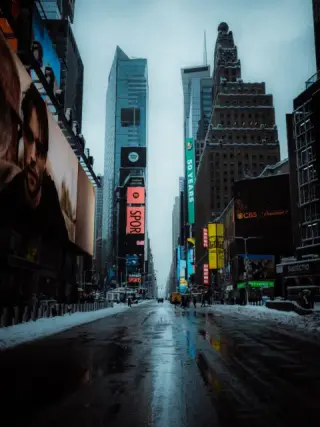Times Square screens reflected in a wet snow-lined street