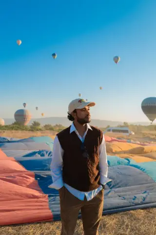 Portrait of a man in a vest surrounded by hot-air balloons.