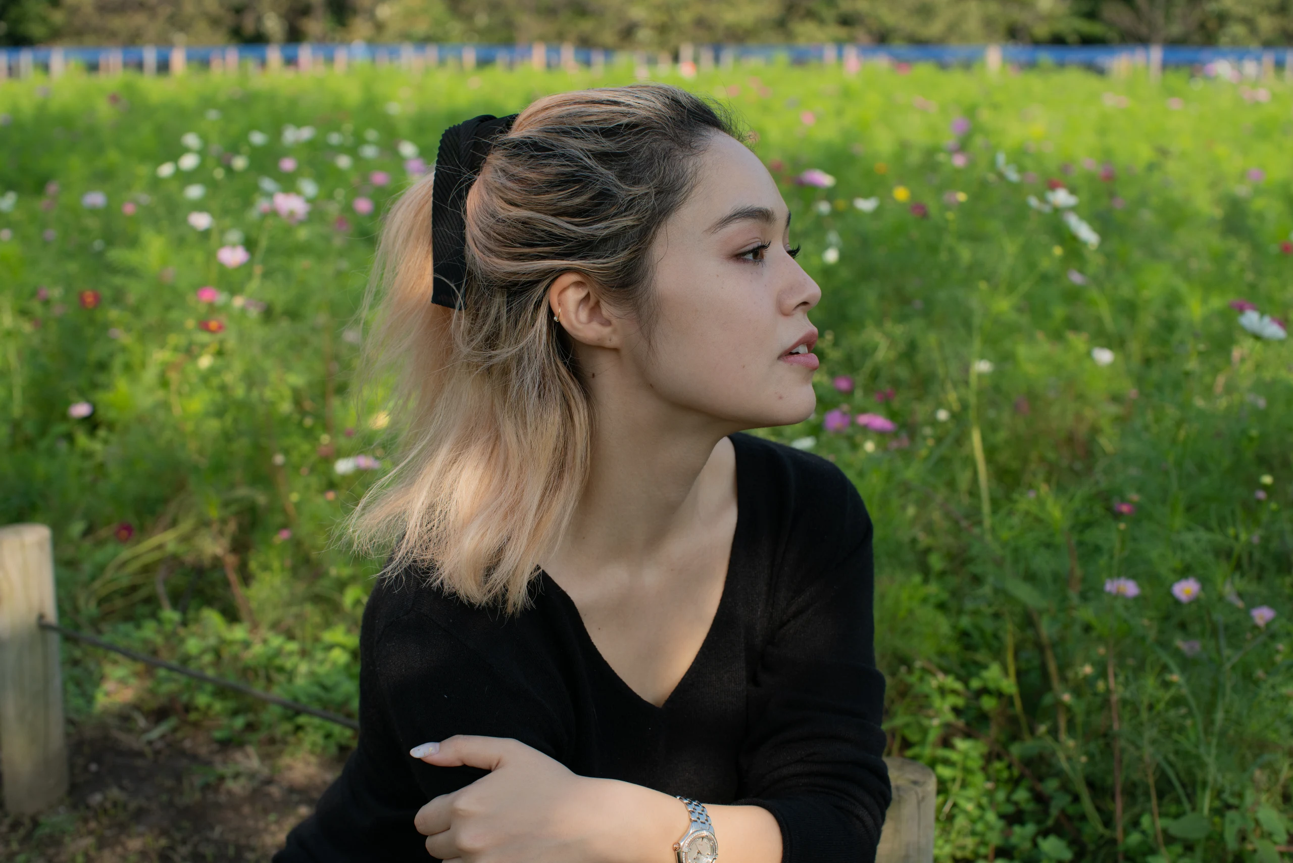 A profile portrait of a woman against green grass and flowers.