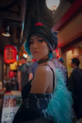 A woman in a pale feathered wrap looks back in a neon-lit restaurant alley.