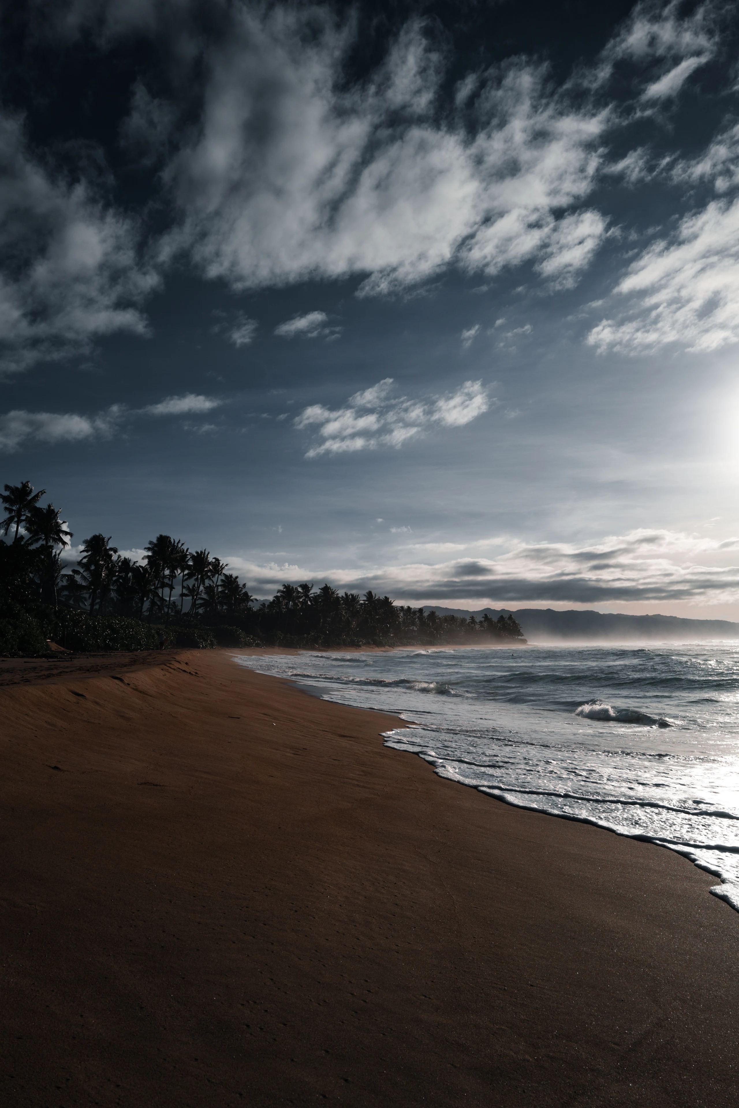 Empty dark beach beneath heavy clouds.