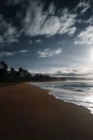 Empty dark beach beneath heavy clouds.
