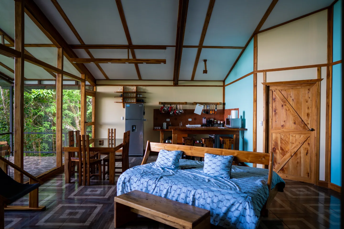 A bright bedroom and sitting area open directly onto a forest-facing terrace.
