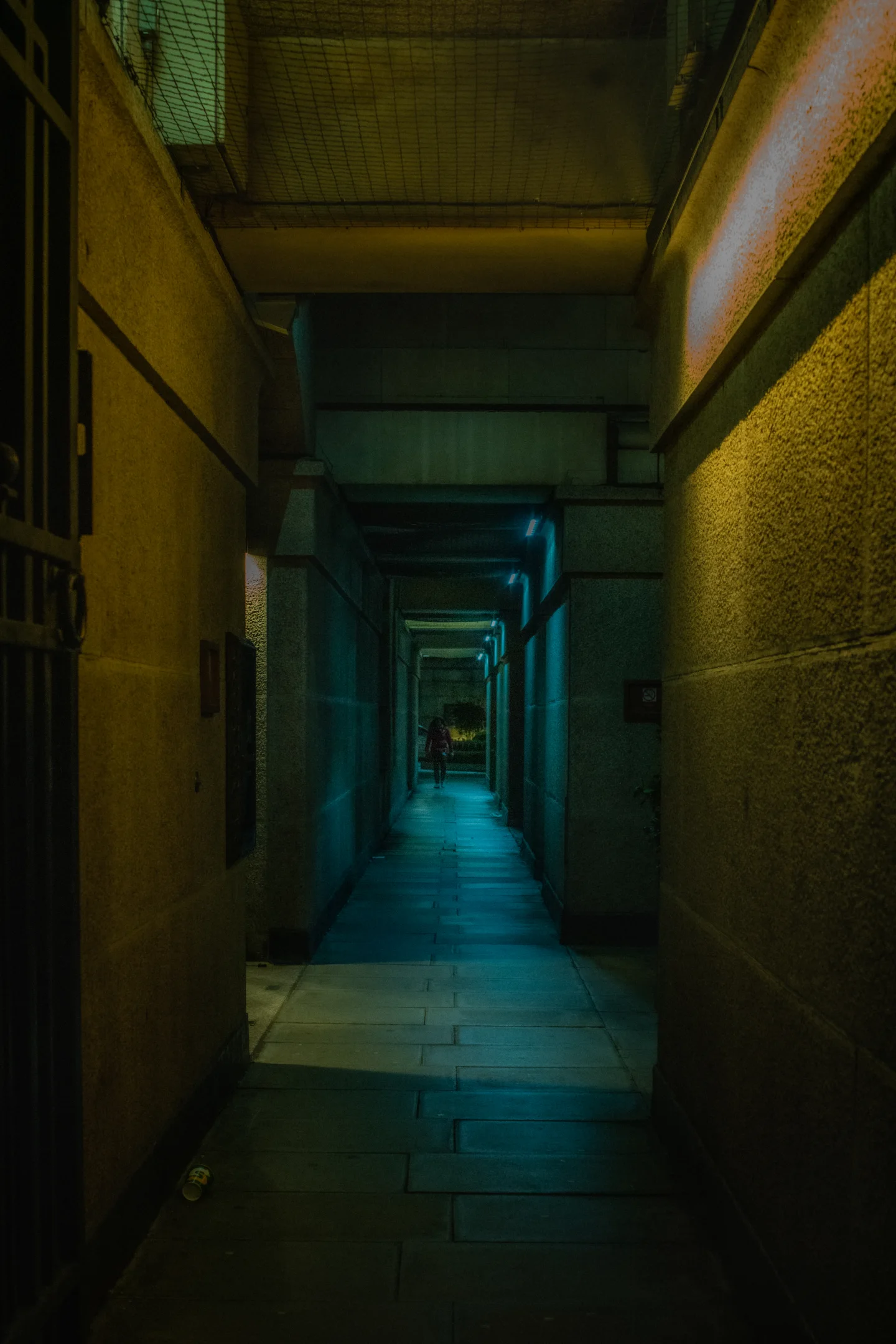 A long blue-green corridor recedes toward a distant pool of light.