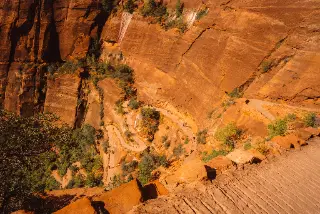 A series of switchbacks crosses an orange Zion cliff viewed from above.
