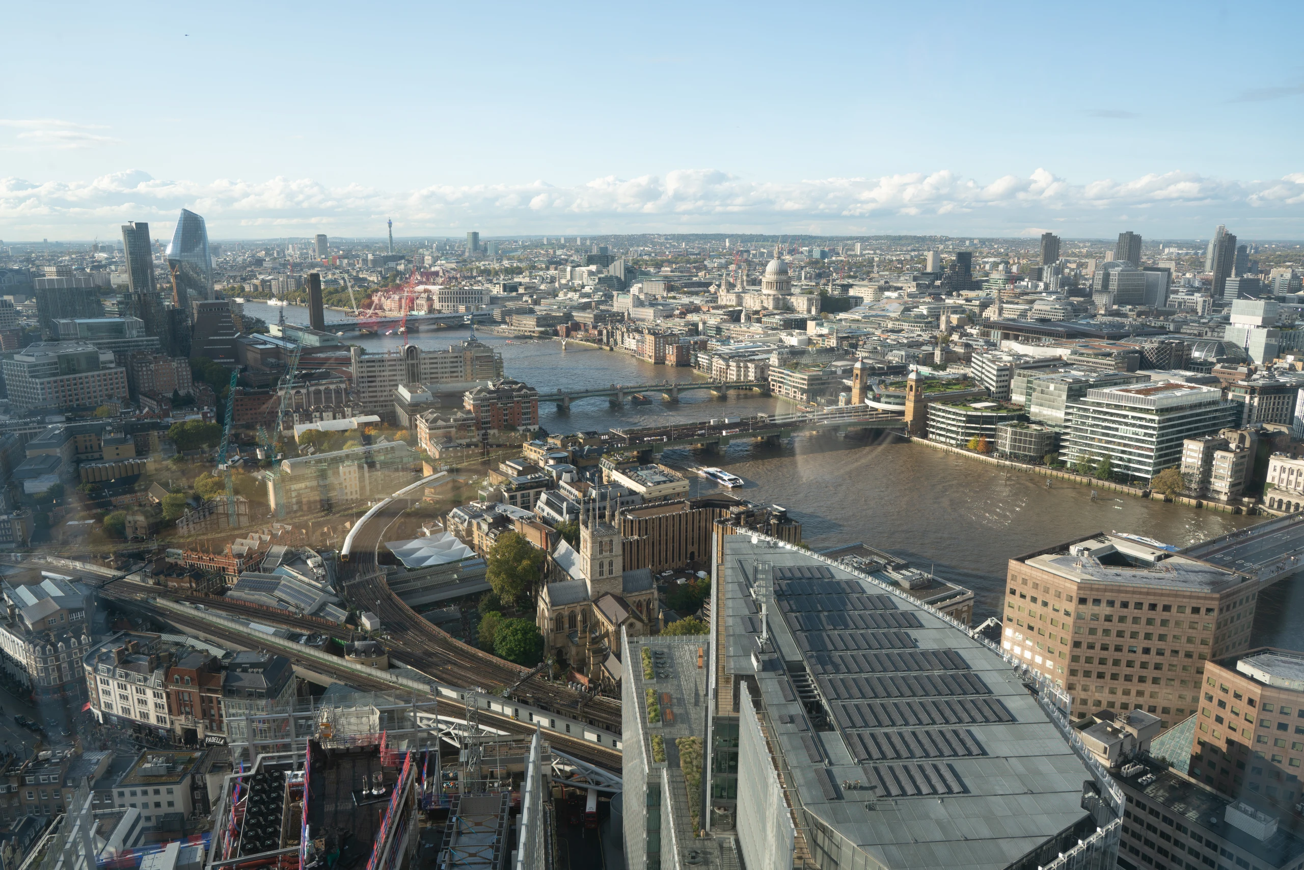 A high daytime view looks across the Thames, bridges, and dense central London.