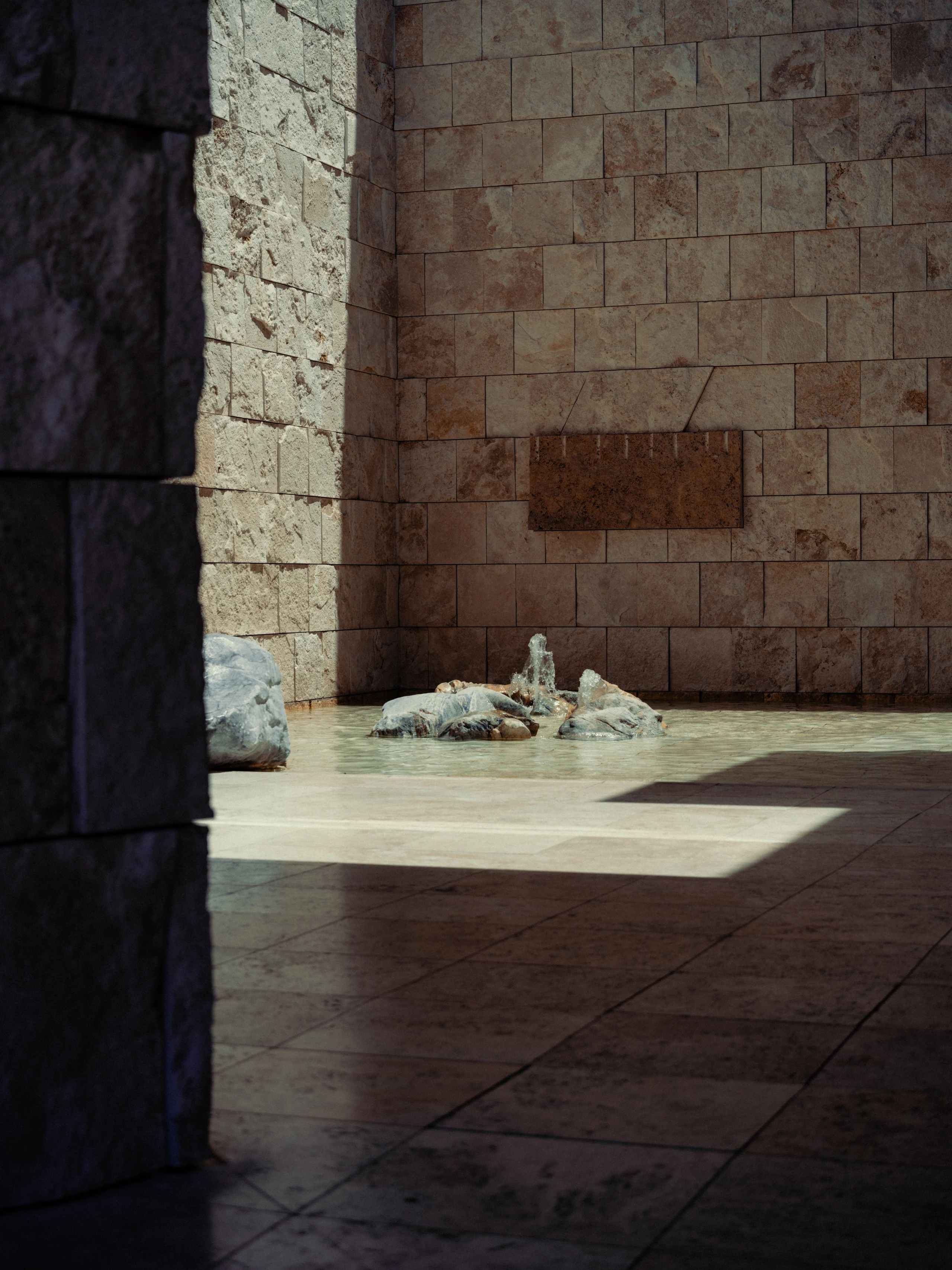 Small fountain and boulders in a sunlit stone courtyard at the Getty Center